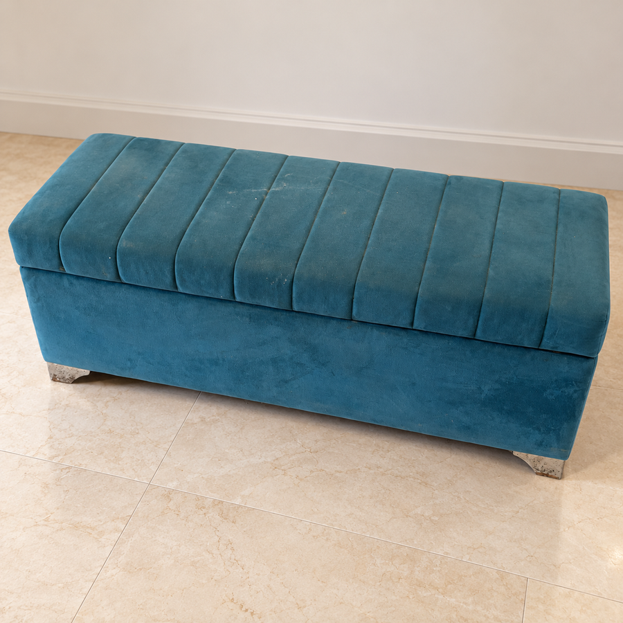 Regularly used teal upholstered backless bench with visible spots and worn edges