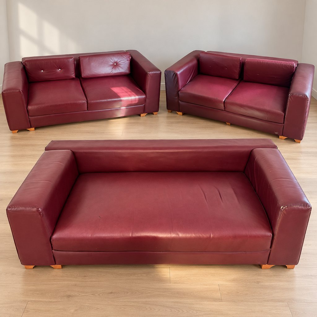 Three distinct maroon upholstered sofa pieces with visible wear