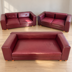 Three distinct maroon upholstered sofa pieces with visible wear