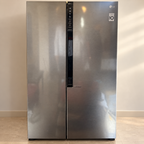 Pre-owned LG side-by-side refrigerator with exterior smudges visible in neutral room