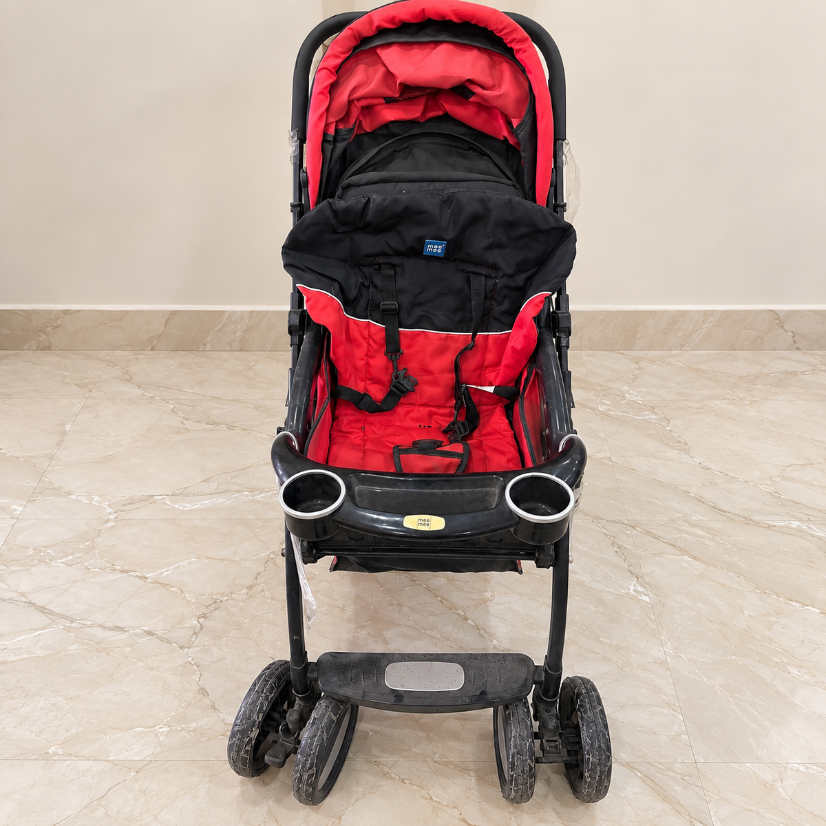 Pre-owned red and black Mee Mee stroller with visible wear, staged in a neutral room